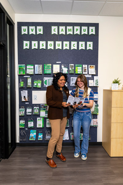 A smiling student with her arms raised in the Fulton Library.