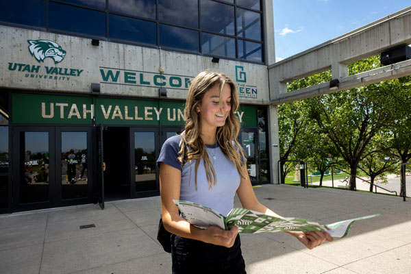 smiling student looking at UVU information brochure