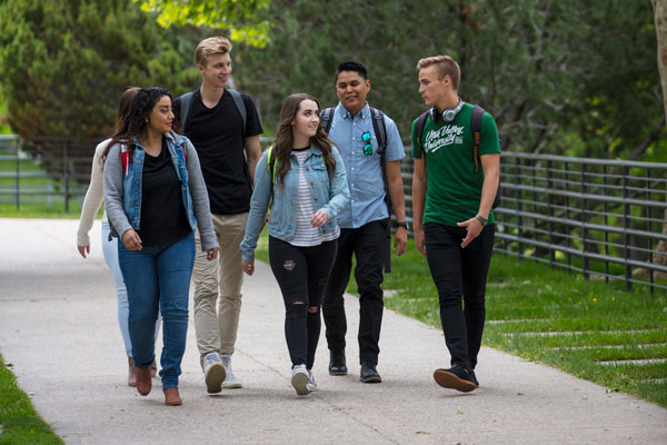 group of UVU students talking together as they walk on campus.