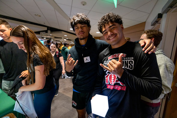 UVU students with their arms around each other showing the hang loose sign