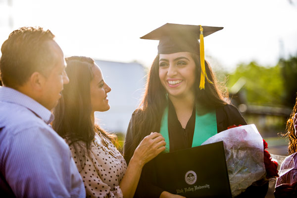 Women in cap and gown walking with child