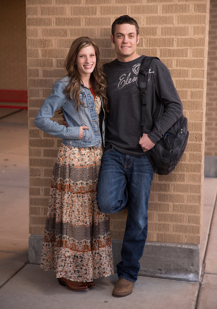 Hetero couple standing side-by-side against a brick background