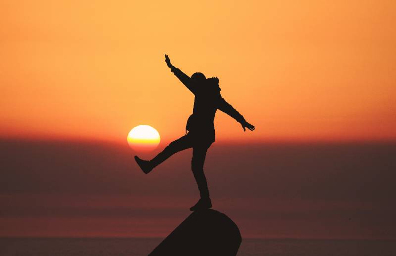 person standing on a rock at sunset