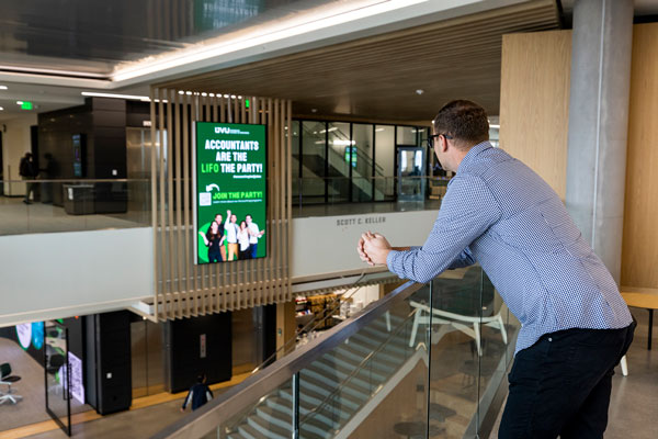 student overlooking digital signage, which is goverened by free speech policies, on UVU campus