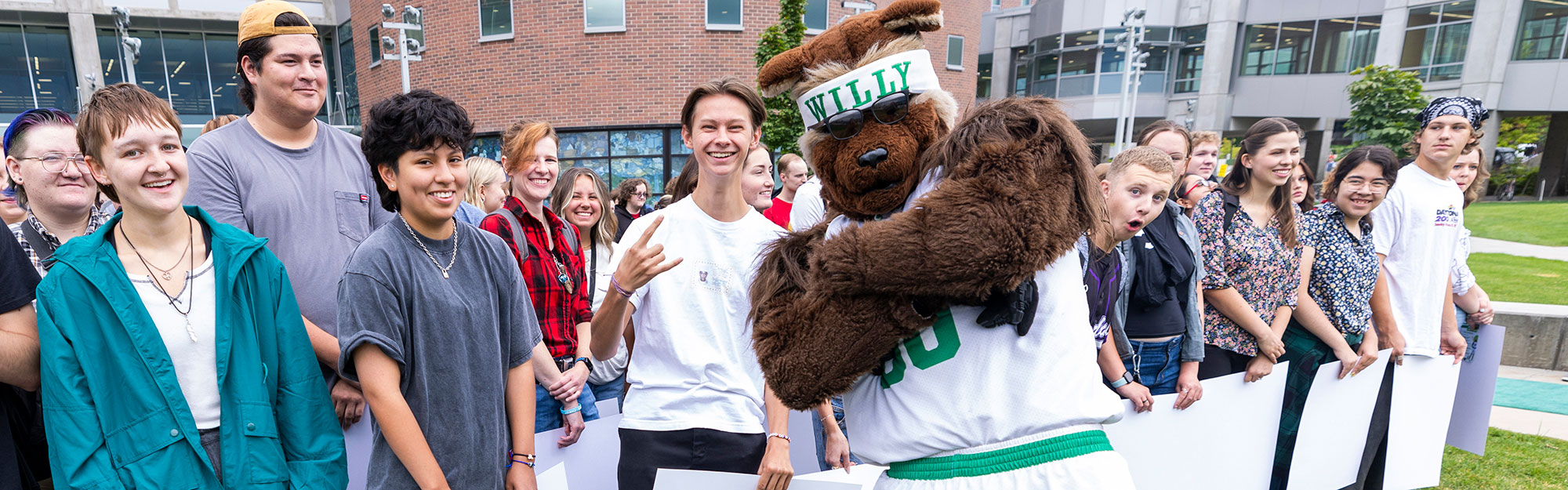 Willy the Wolverine posing with smiling students on campus