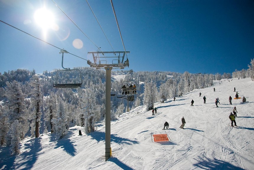 Crowded chairlift and ski run on sunny winter day