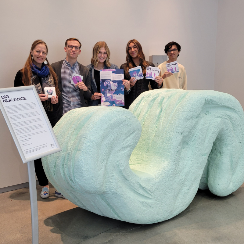 a group of five people standing behind a six-foot-long packing peanut sculpture