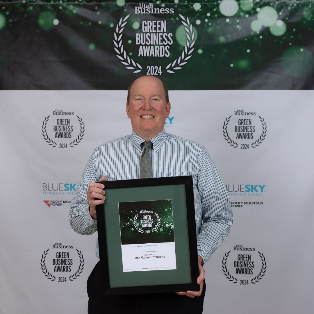 a man smiling and holding a framed award certificate