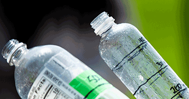 Two plastic water bottles, with grass in the background.