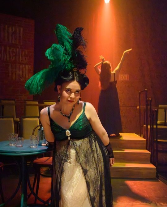 Two actresses posing, one facing forward and the other facing backward, with dramatic lighting