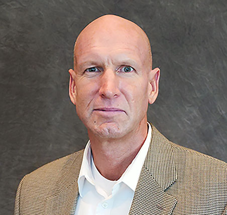 Photo of Jared Ellison  a caucasian male who is bald, wearing a tan suit coat and white dress shirt