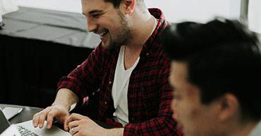 man typing on laptop smiling