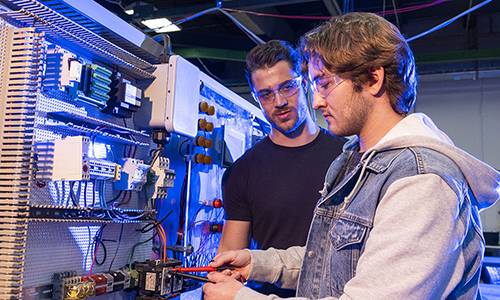 Two students working on electrical circuitboard