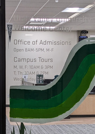 The Office of Admissions window with the hours of operation written on it. (Open 8AM - 5PM, Monday - Friday)