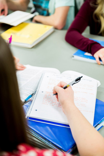 A woman writing something in a notebook with a black pen.