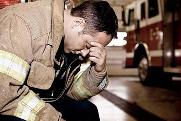 Fireman sitting on front of truck with head in hand