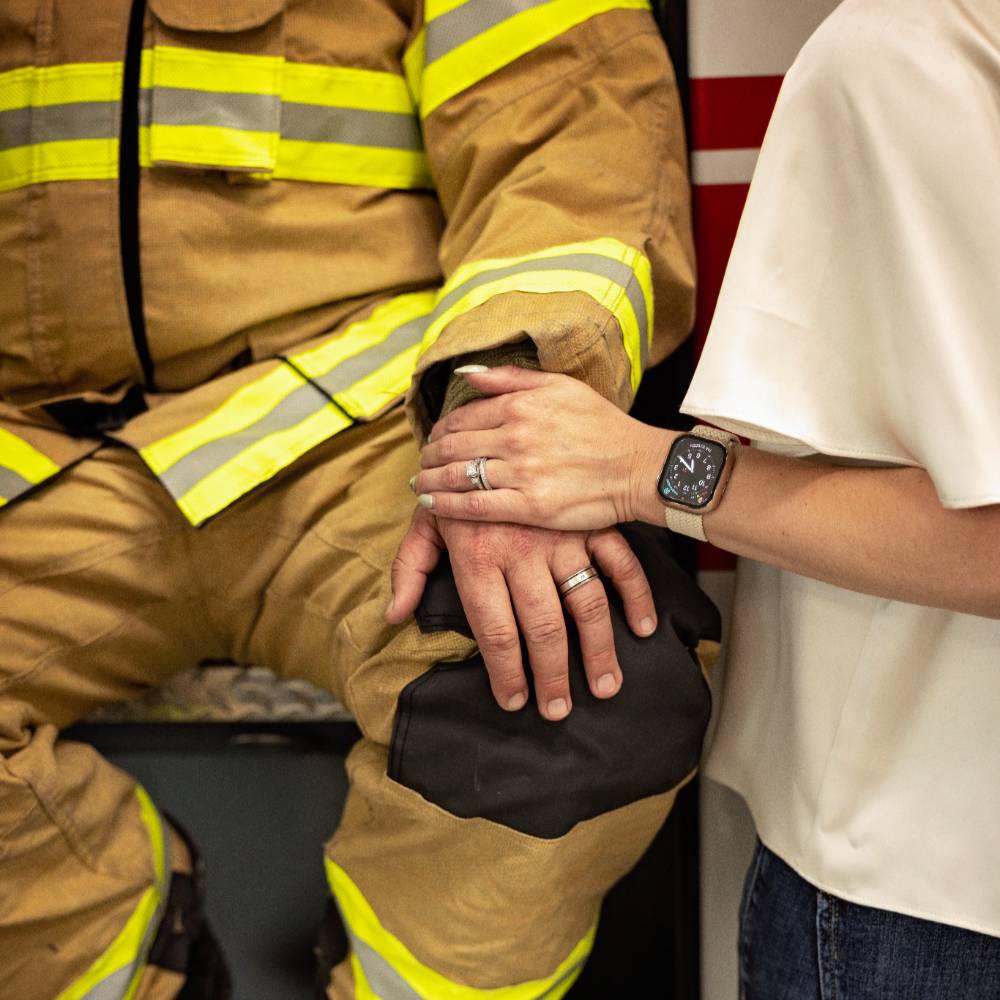 firefighter sitting with person holding their hand
