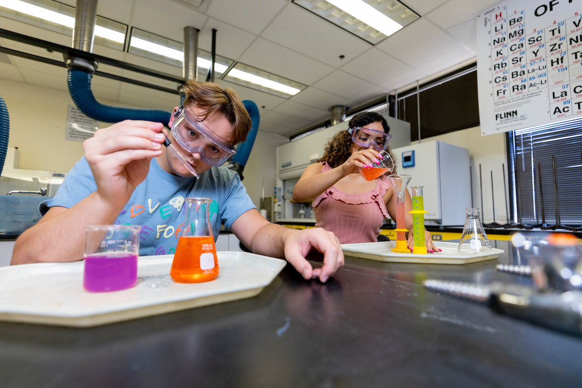 Students in a science lab pouring liquids into beakers
