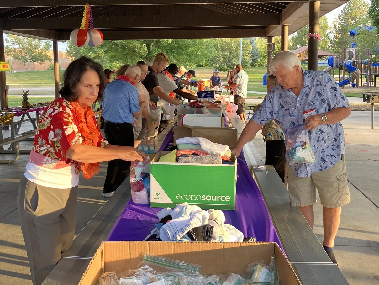 Volunteers assembling hygiene kits at long tables.