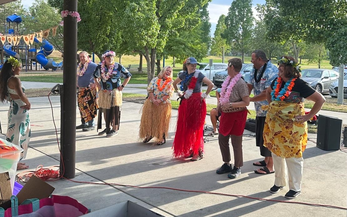 Rotarians and Rotaractors dancing and performing with ukulele, hula dancer in the background.