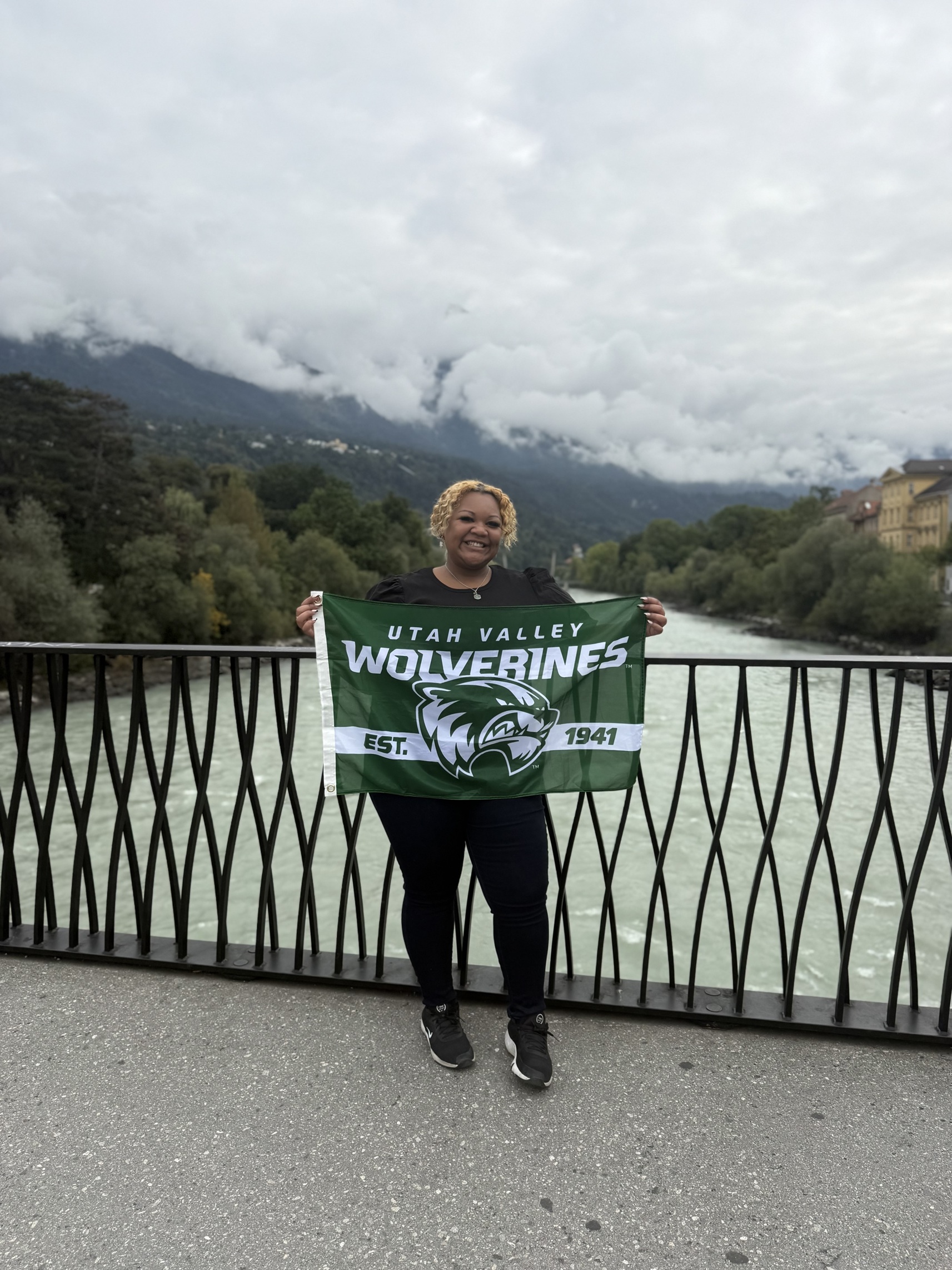 anessa- Michelle Purcell holding the UVU flag on the Innsbruck bridge.