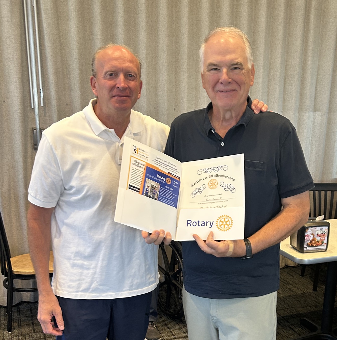 Rotarian Clark  Merkley presents new member Curtis Turnbull with his Rotary membership certificate