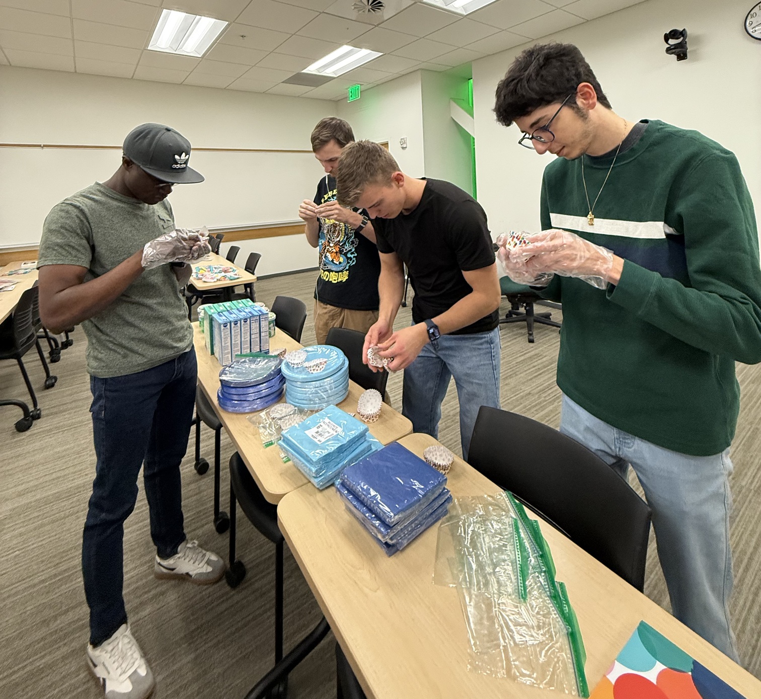 Group members putting cupcake liners in individual bags for the birthday kits