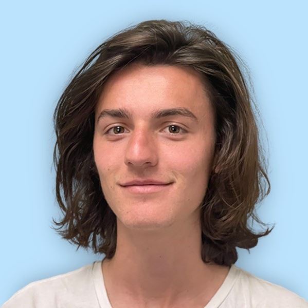 Young man smiling with long, dark brown hair
