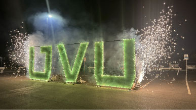 A lit up UVU sign with fireworks on each side