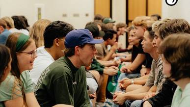 Students sitting across each other in lines, talking with one another.