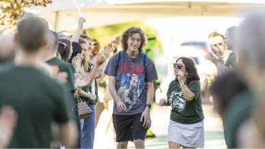 Male student walking next to a female employee through a crowd of people on each side of them