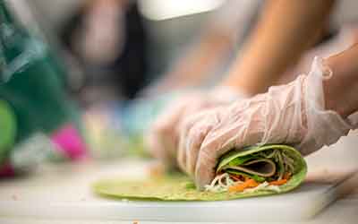 Hands rolling up a healthy turkey wrap
