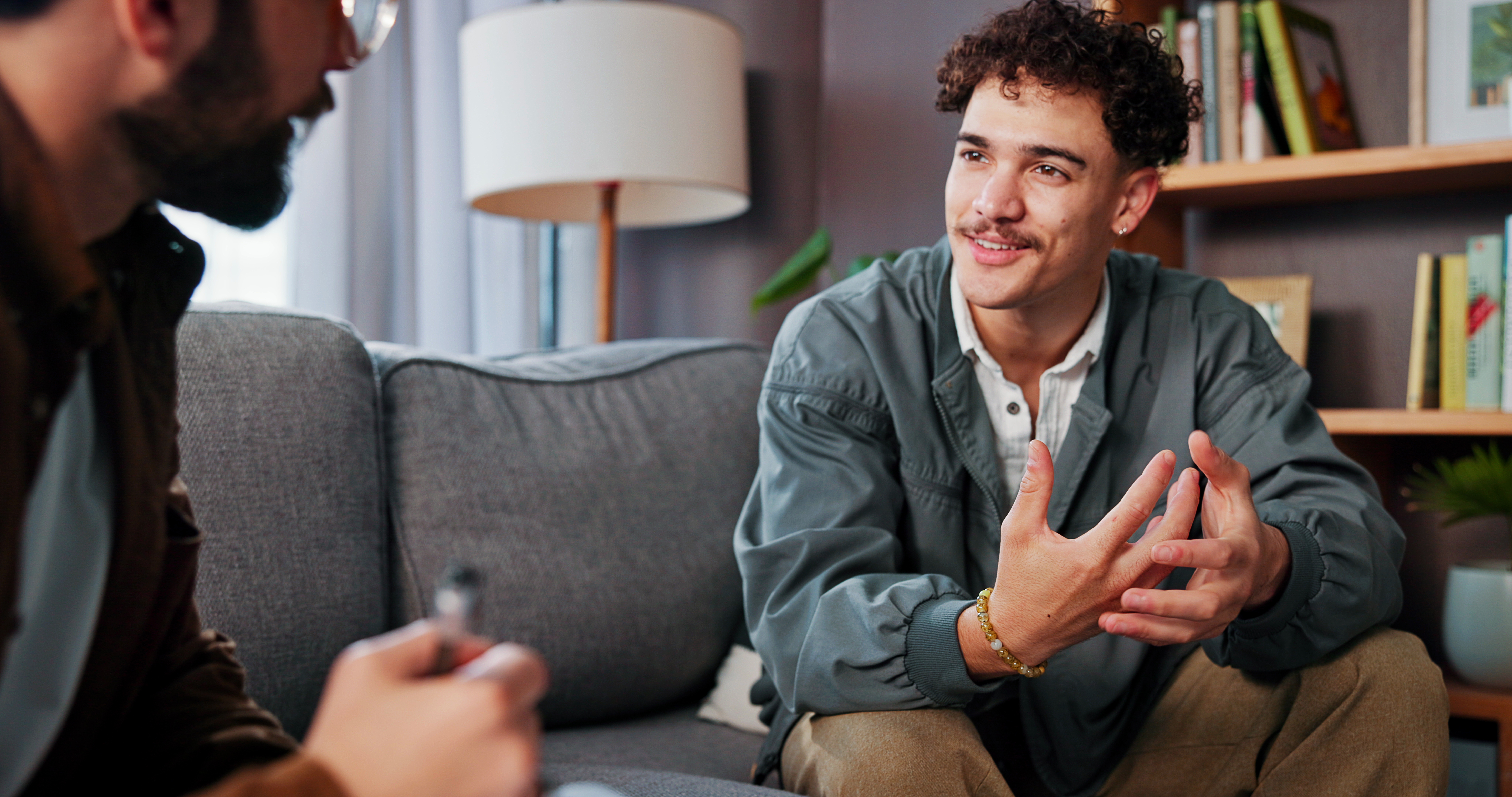 Two men having a discussion while sitting on the couch.