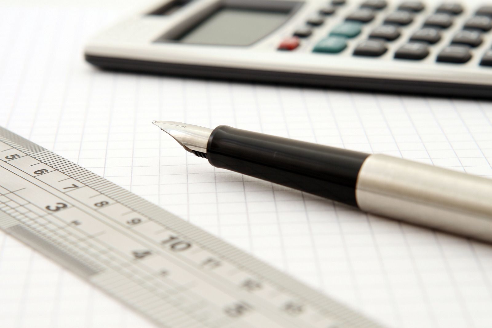 Pen, calculator, and ruler lying on a sheet of graph paper