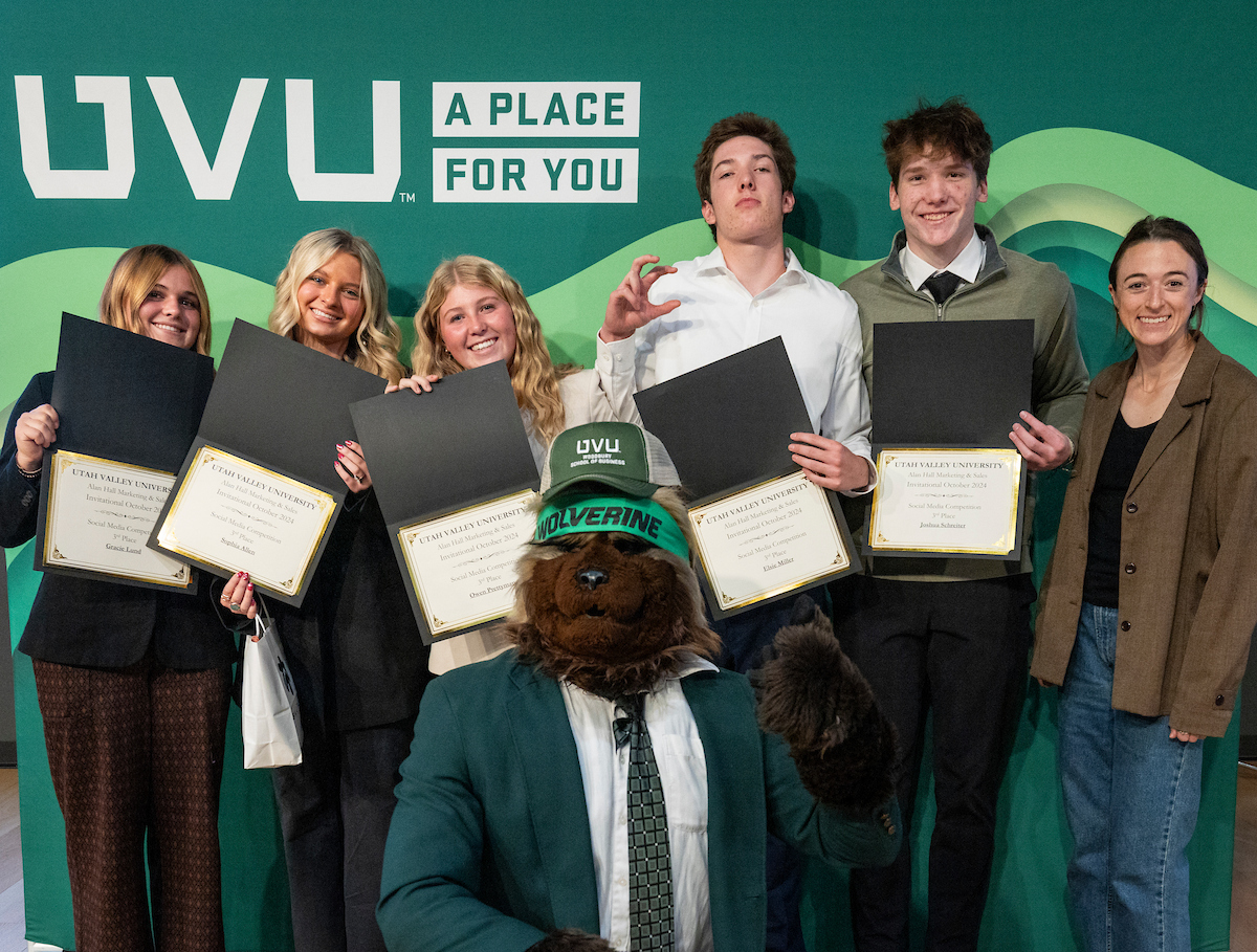 Students excited in front of green backdrop with UVU logo