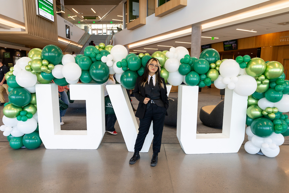Female student in front of large UVU block letters and multi colored balloons