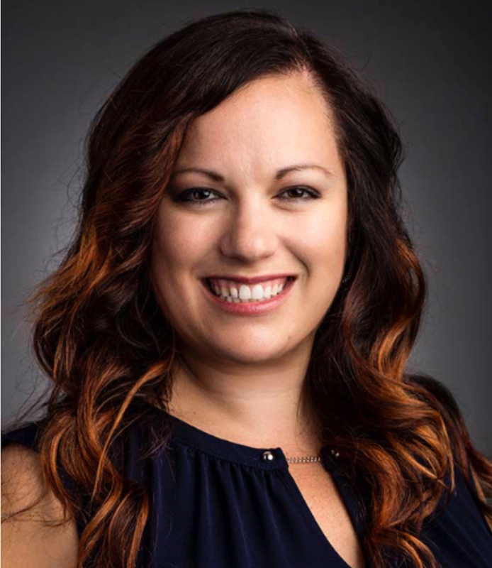 Profile photo of Jessica Ballard, standing in front of a gray back ground smiling forward