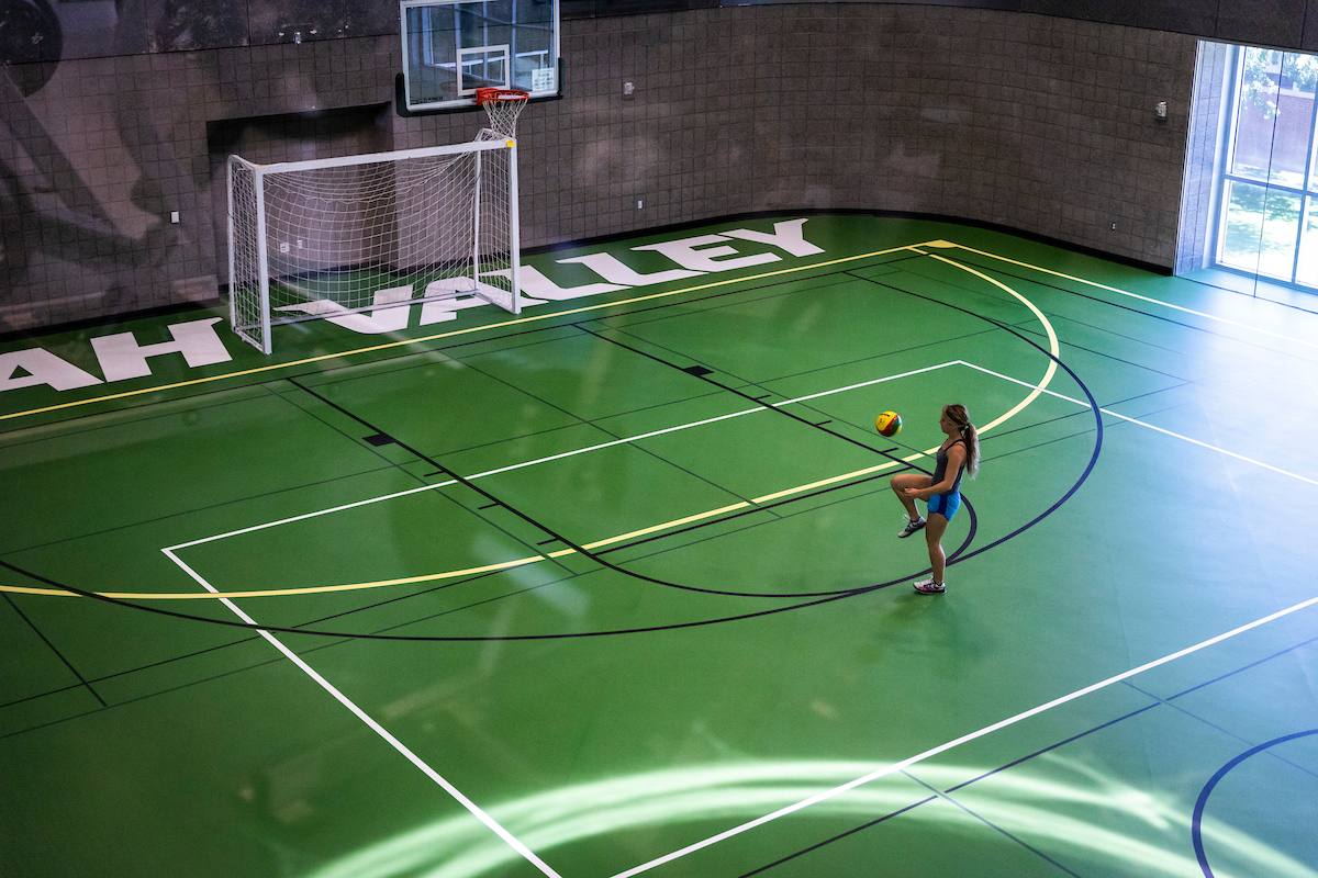 A girl playing basketball alone in a gym at UVU