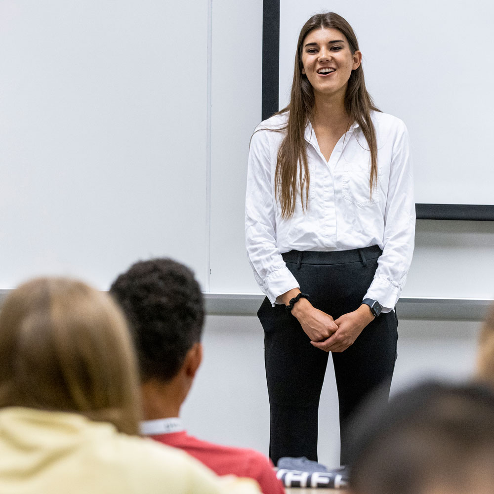A woman standing in front of students in a lecture hall